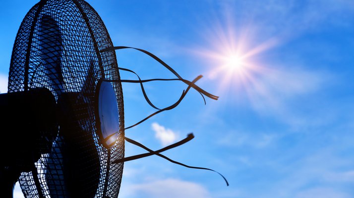 Auf dem Bild ist ein Ventilator vor blauem Himmel und strahlender Sonne abgebildet.