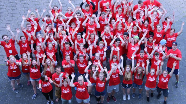 Eine Gruppe von fröhlichen Menschen in roten Volunteershirts.